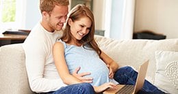 pregnant woman and husband looking at computer